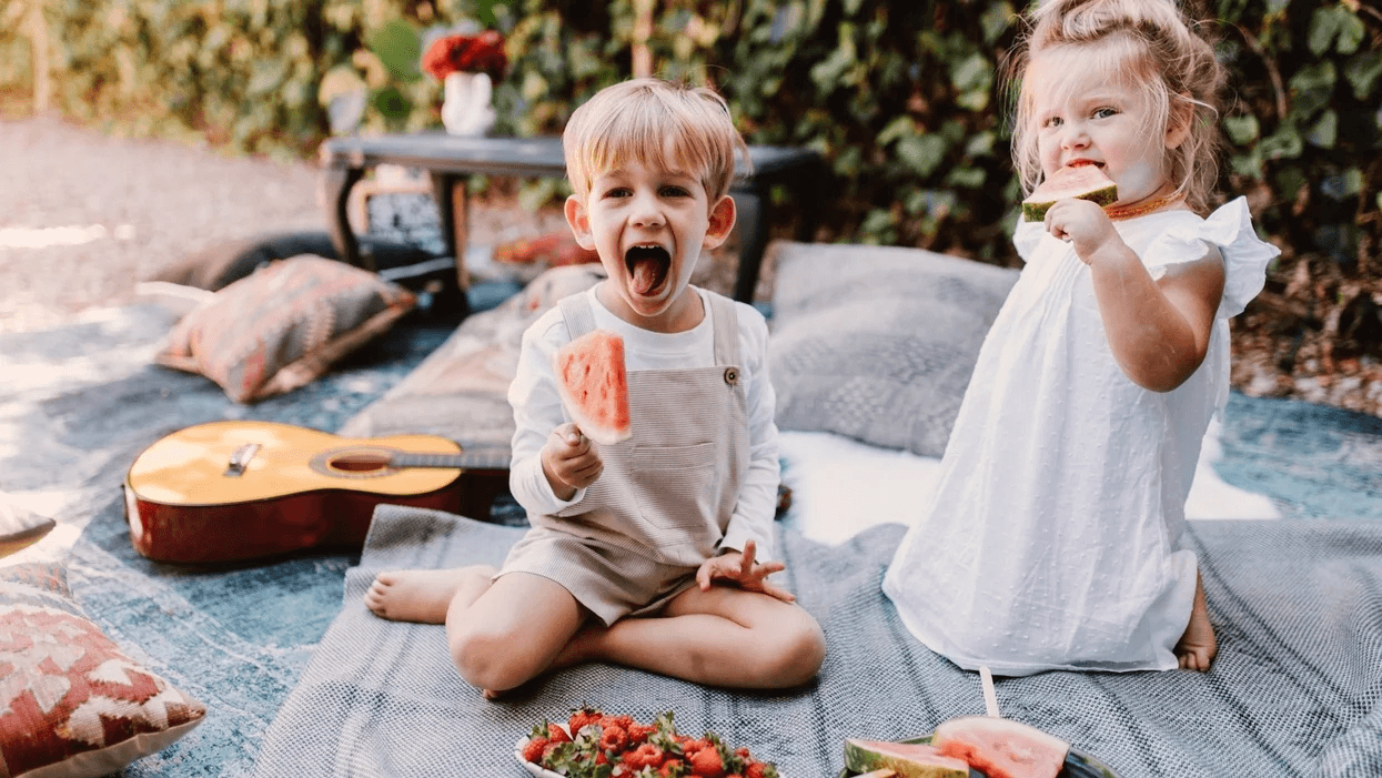 kids eating watermelon on a picnic blanket