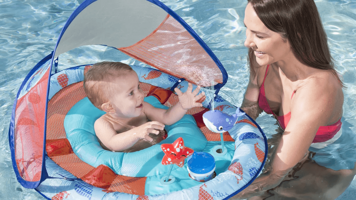 mom holding baby in a puddle jumper in the pool