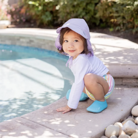 little girl wearing a hat by a pool