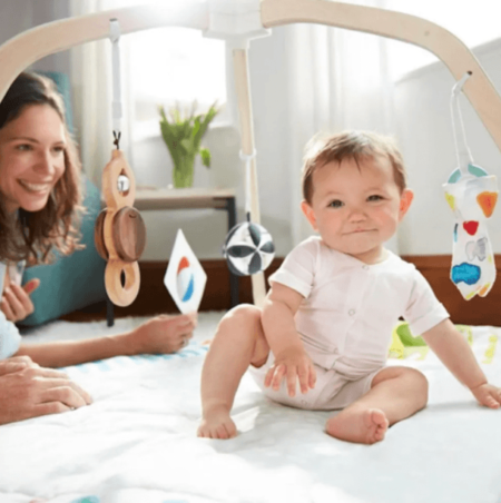 baby on a playgym while mom watches