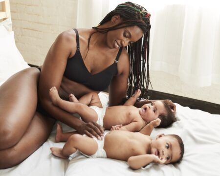 Mom wearing nursing bra and playing with her twins on a bed - best stylish nursing bras