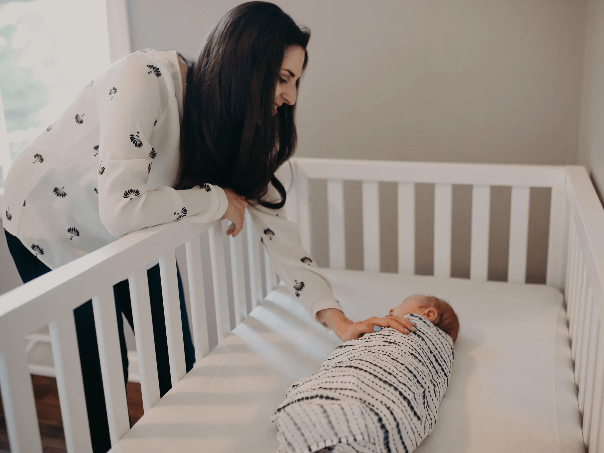 mom checking on newborn in crib