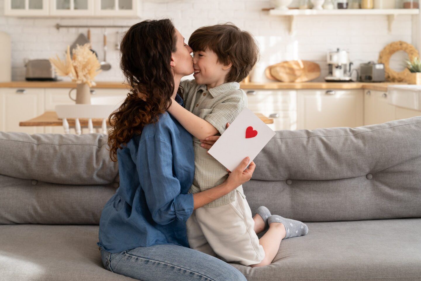 mom kissing sensitive son on cheek holding a handmade card