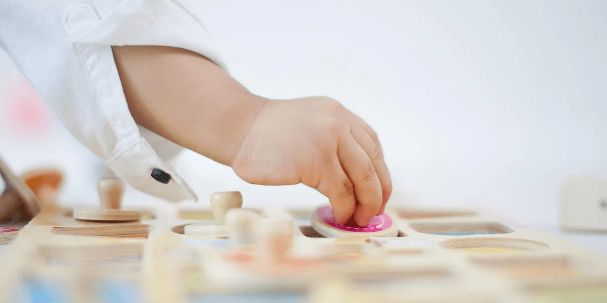 toddler hand playing with a wooden puzzle
