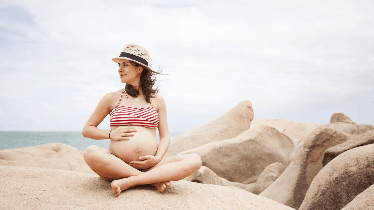 pregnant woman holding belly on sand dunes