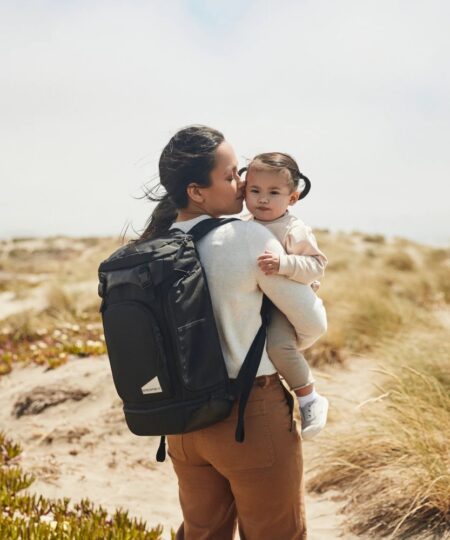 mom carrying her daughter wearing a No Reception Club backpack, a great bag for baby's first flight