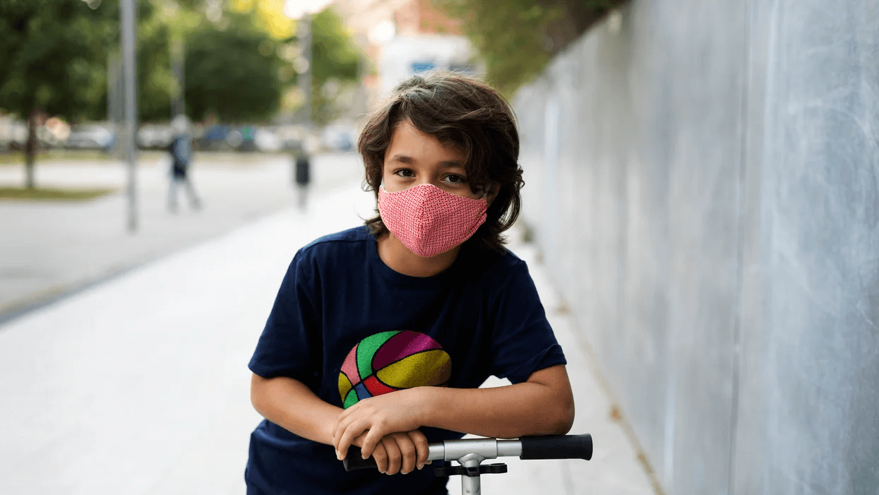 child wearing face mask on a scooter