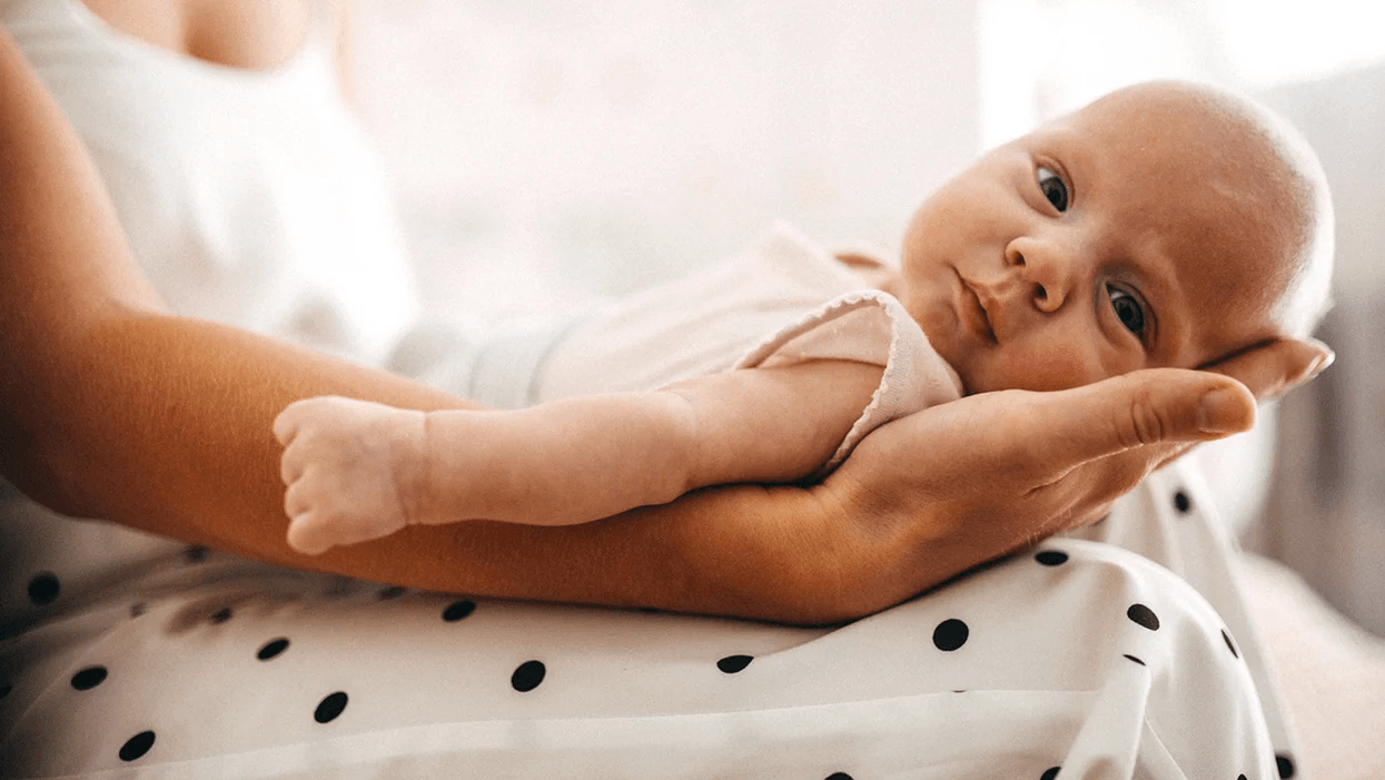 mom holding newborn baby on her lap while he looks at camera