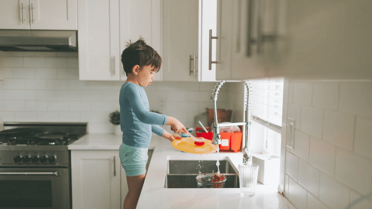 child washing dishes in the sink