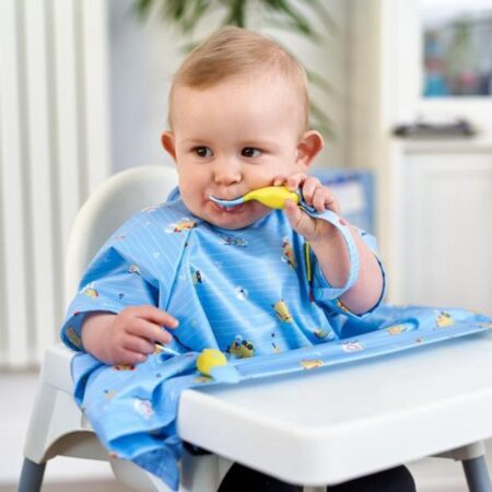 Premium Photo  A small child sits on a highchair and eats food from a  plate with a spoon. baby silicone utensils for feeding babies