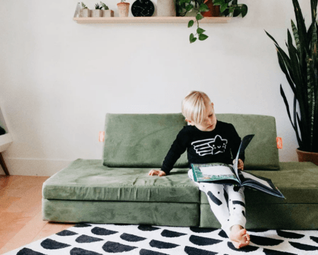 child reading book on nugget couch Motherly