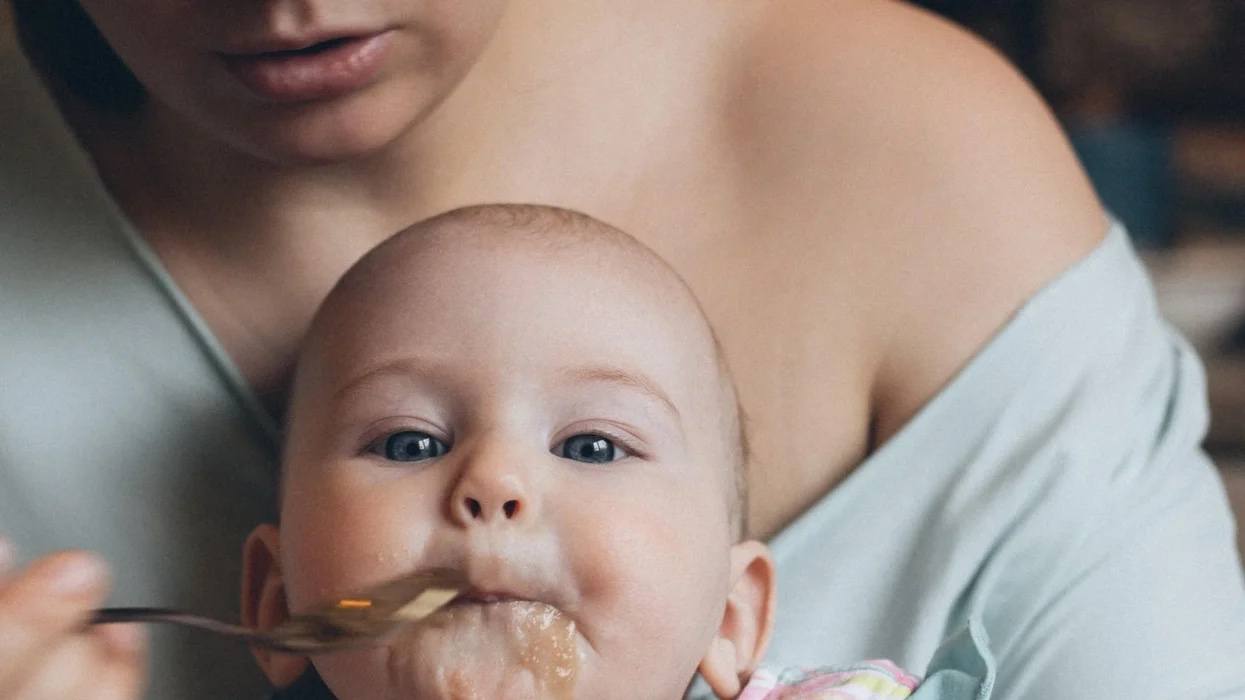 mom spoon-feeding a baby - 9-month-old feeding schedule