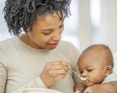 mom feeding baby food Motherly