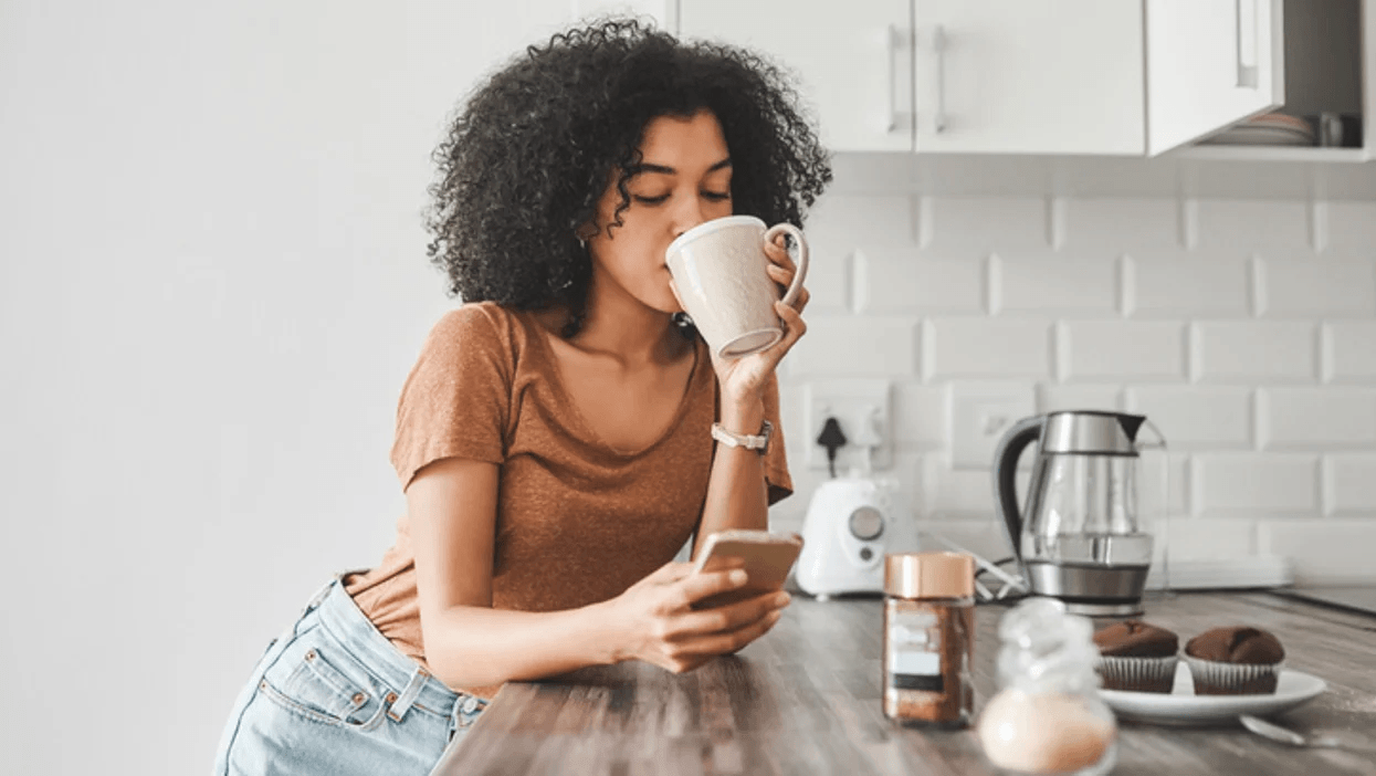 woman on her phone drinking a cup of coffee