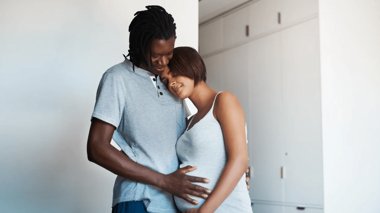 african american couple embracing dad holding moms pregnant belly