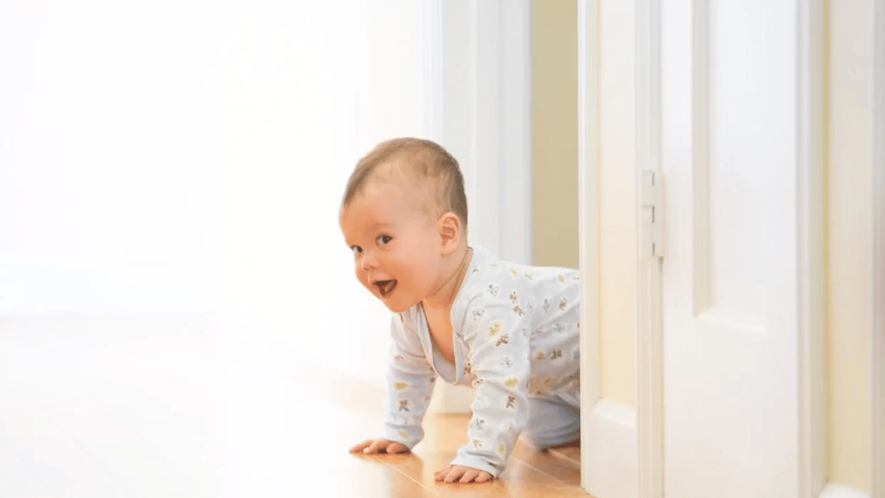 baby peeking around the corner crawling, one of the 8-month milestones for baby