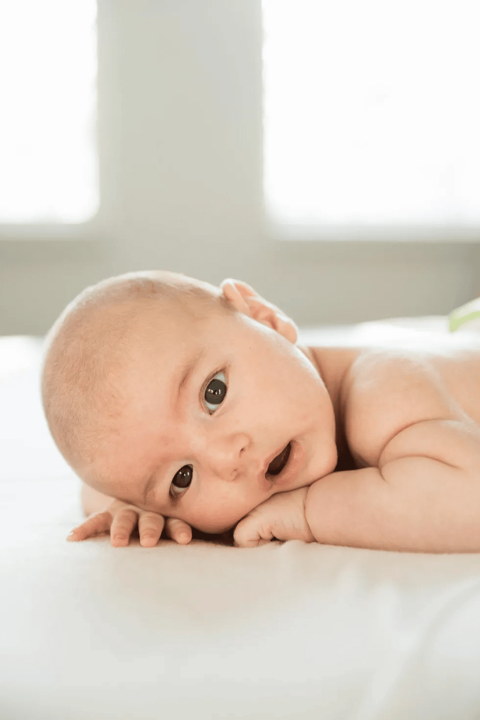 cute baby laying on its stomach and making sustained eye contact, one of the 2-month milestones