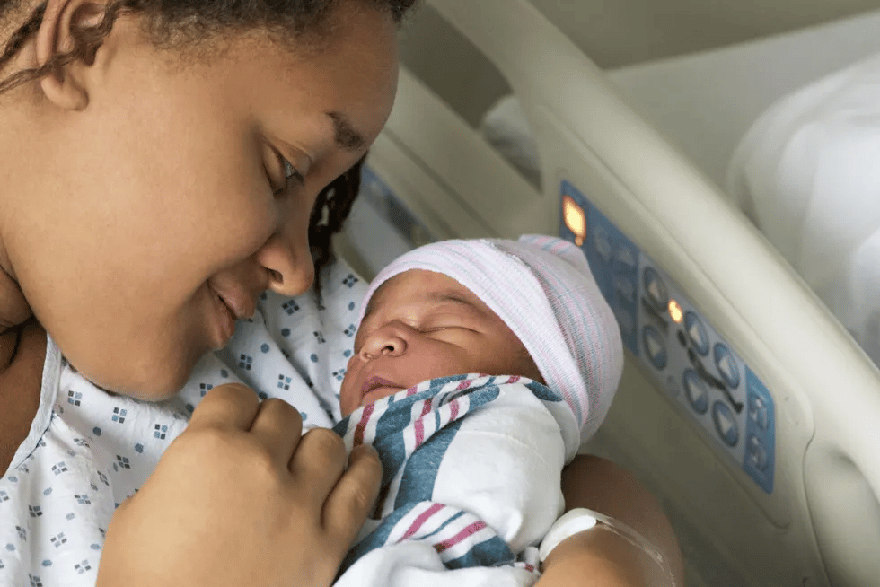 black mother holding newborn in hospital Motherly