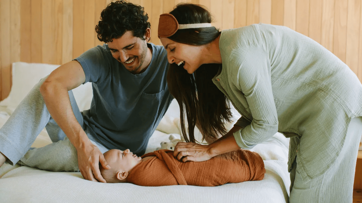 family-laying-on-a-bed-with-a-newborn-swaddled