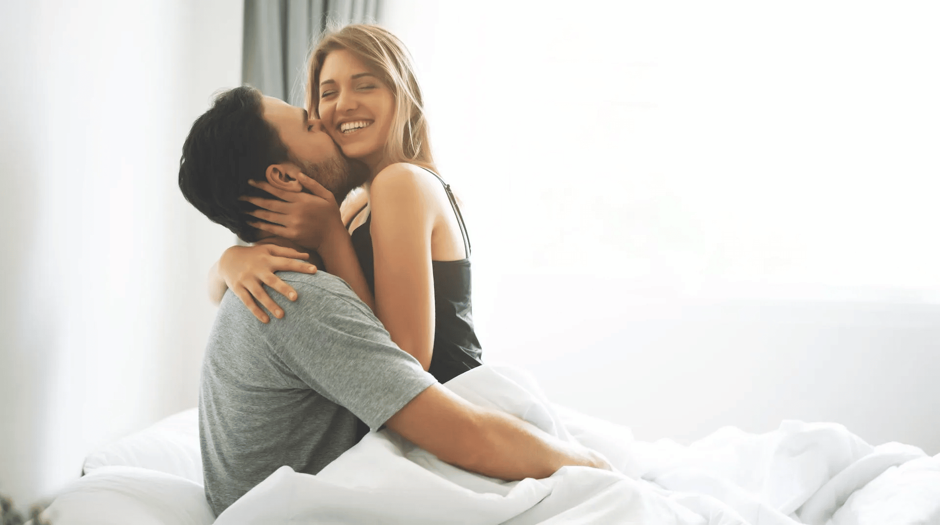 couple in bed smiling kissing 1 Motherly