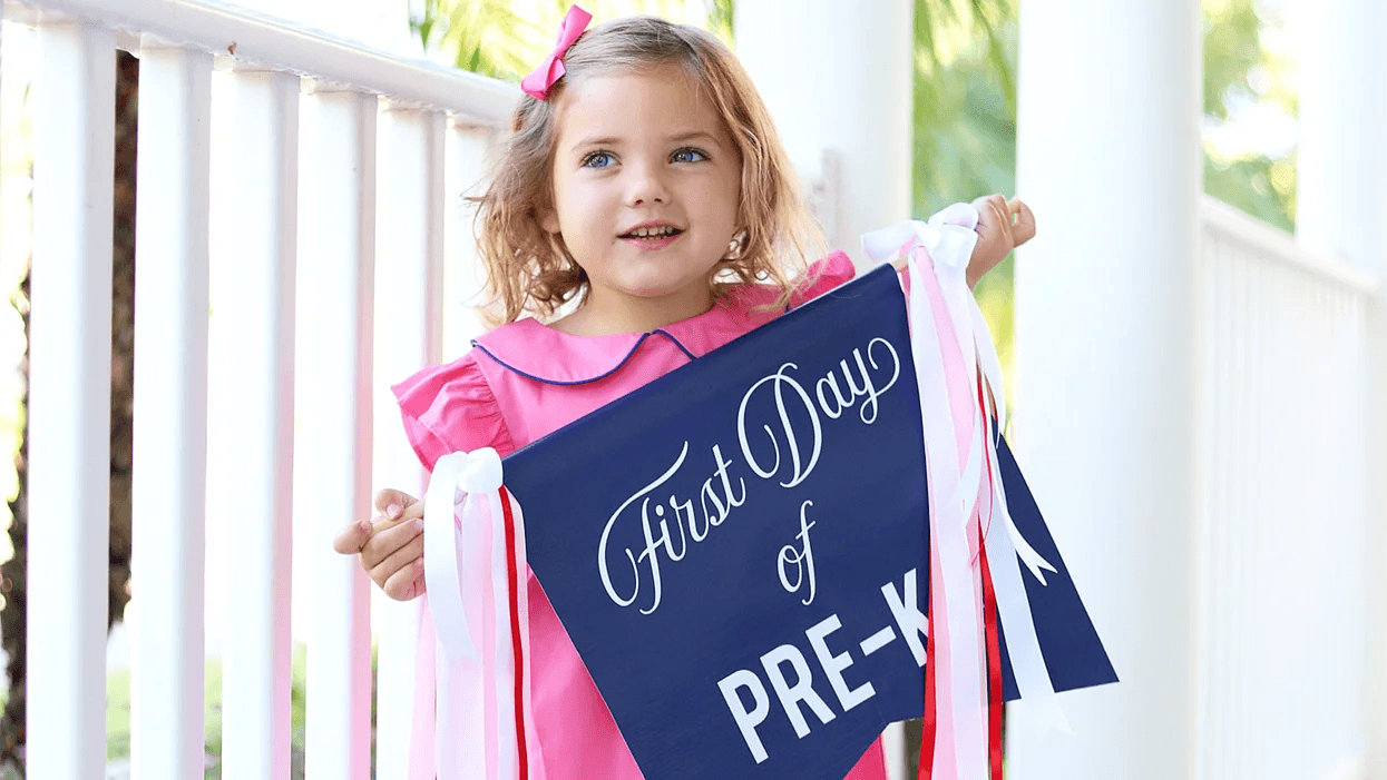 young girl holding first day of preschool signs- first day of school board