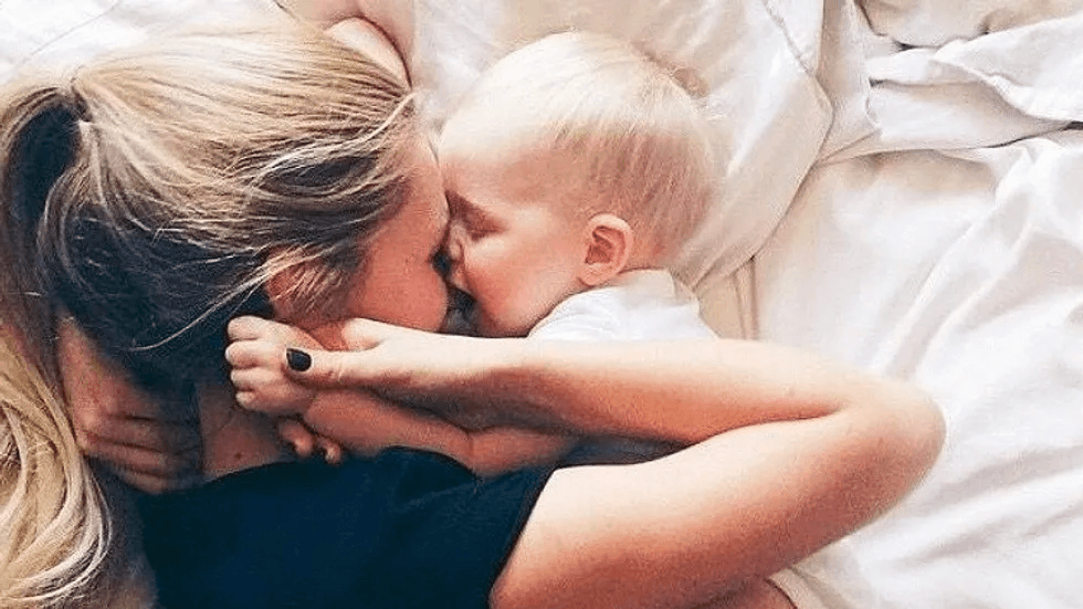 mom laying with baby on a bed