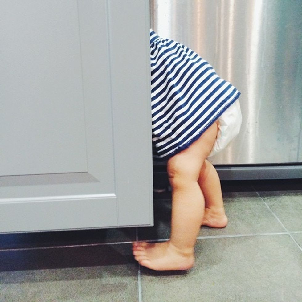 baby discovering its ability to open a cabinet after learning how to walk