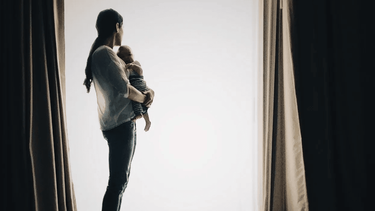 mom holding baby in front of a window