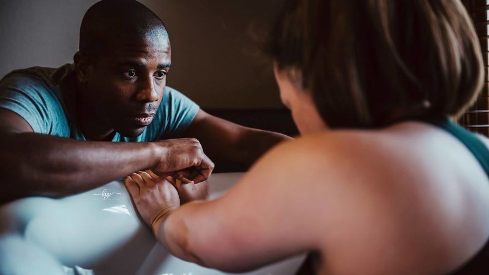 man holding womans hand while she's giving birth