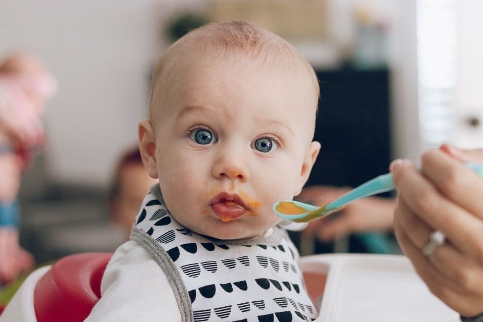 baby being fed orange puree with a blue spoon, a must-capture baby photo