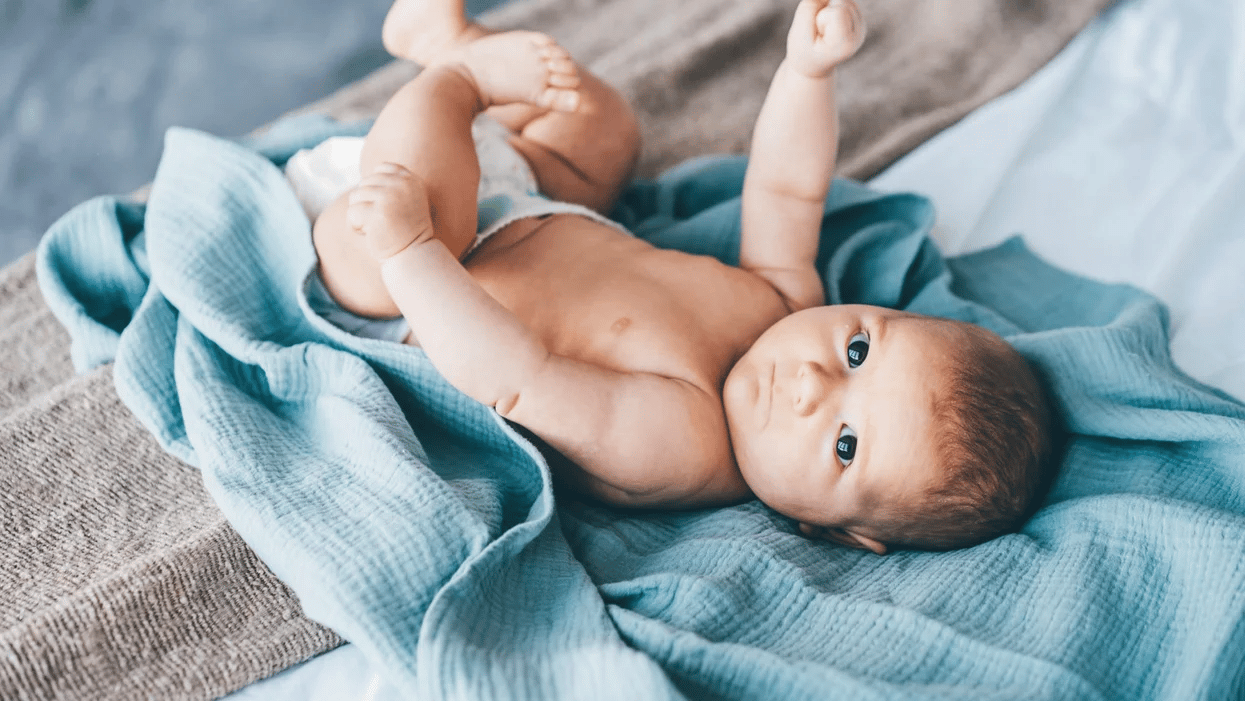 baby laying on a blanket playing with his toys - 6-week-old baby feeding schedule
