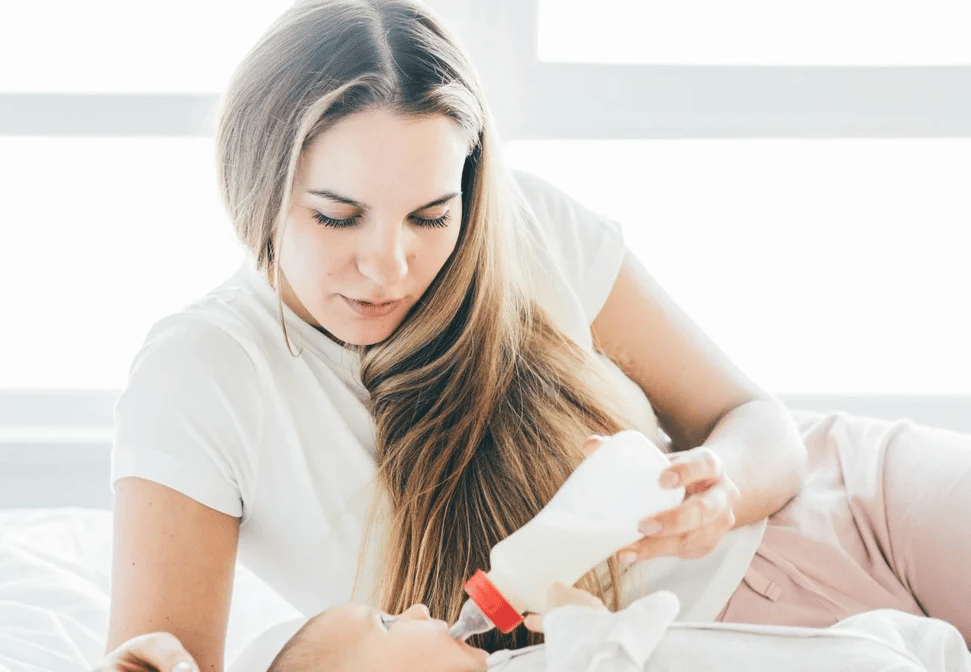 mom giving a baby a bottle - 7-week-old-baby feeding schedule