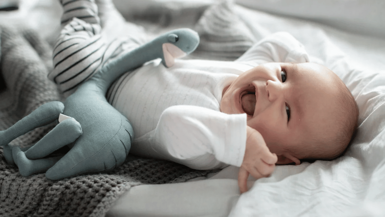 baby laying on a bed and laughing - nine-week-old baby feeding schedule