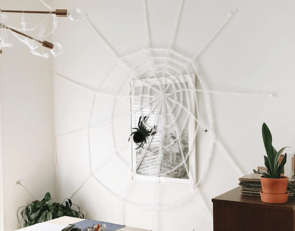 wall-mounted spiderweb made of yarn, a great way to celebrate baby's first halloween