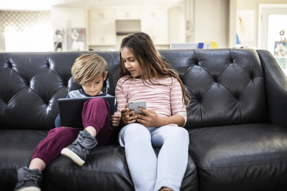 kids using tablet and phone on sofa