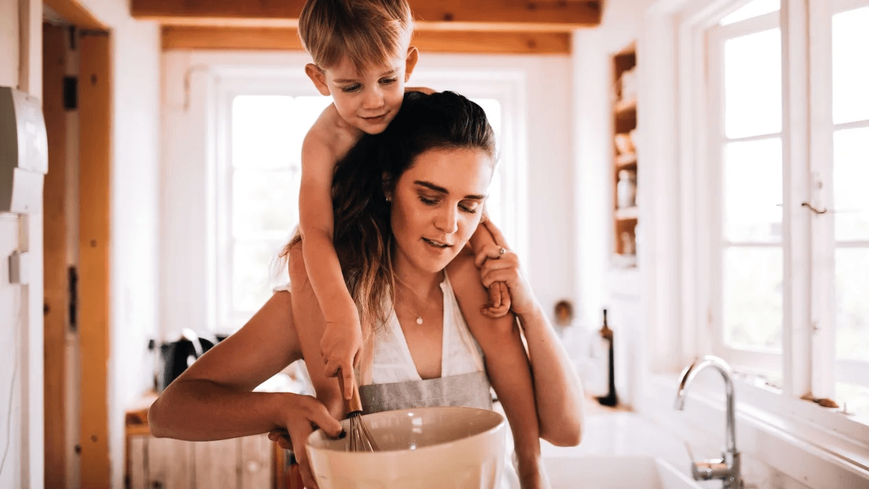 woman cooking with a child on her shoulders