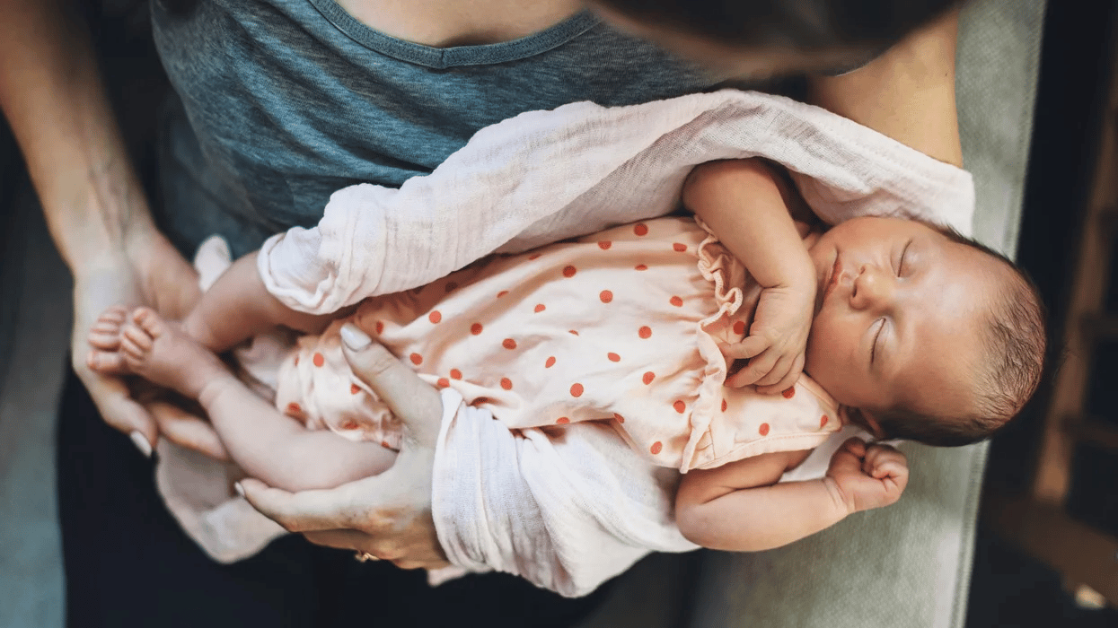 mom holding sleeping newborn Motherly