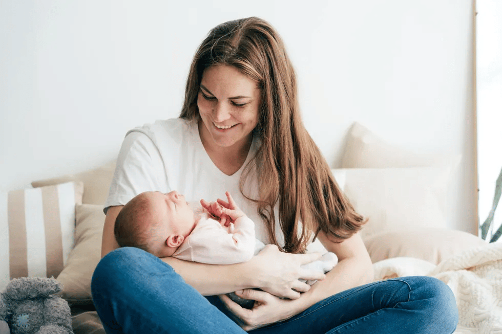 mother holding newborn at home 1 Motherly