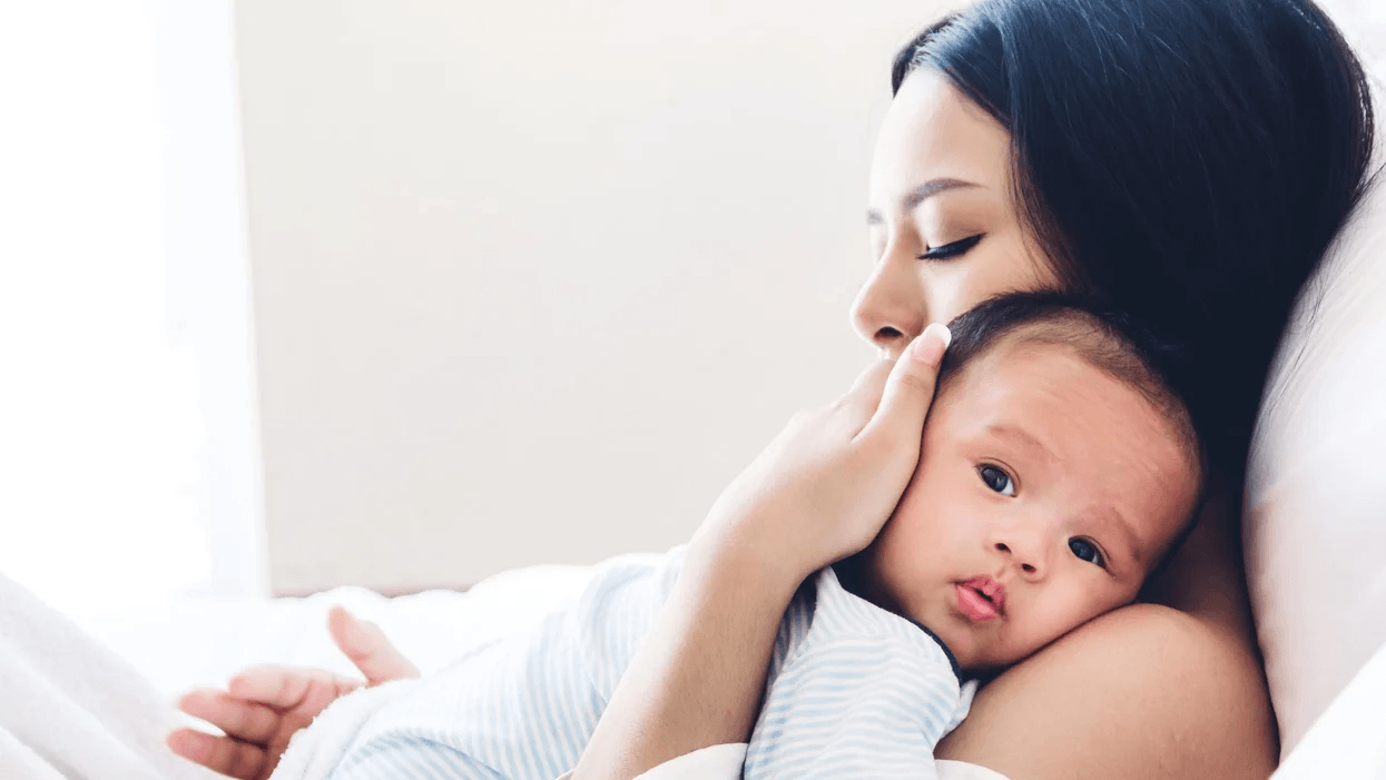 mother holding newborn baby in bed