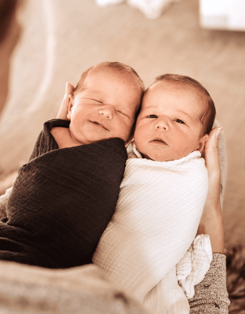 parent holding swaddled twin babies