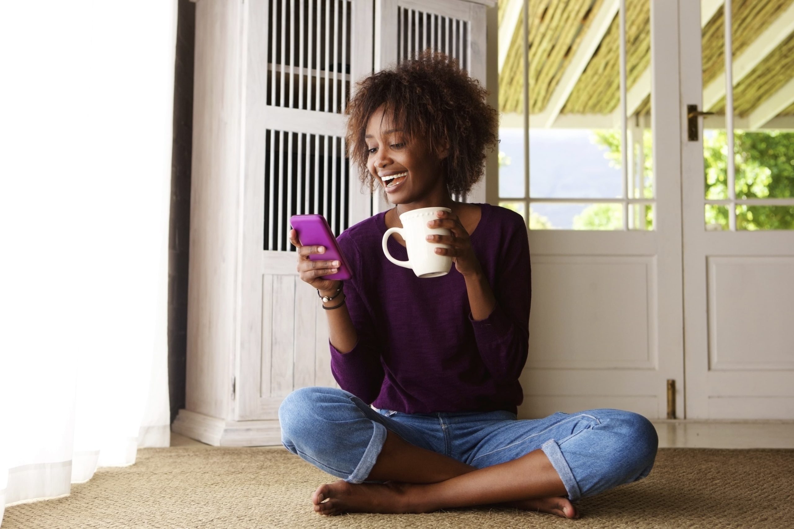 Woman sitting outside with a cup of coffee on phone