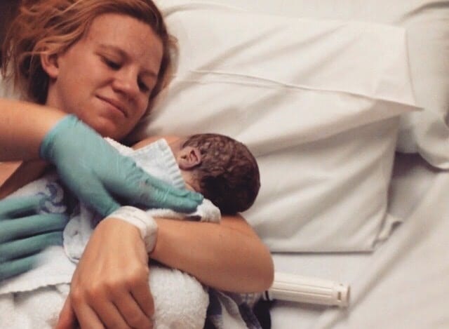 mom holding newborn baby in a hospital wanting to thank her labor & delivery nurse