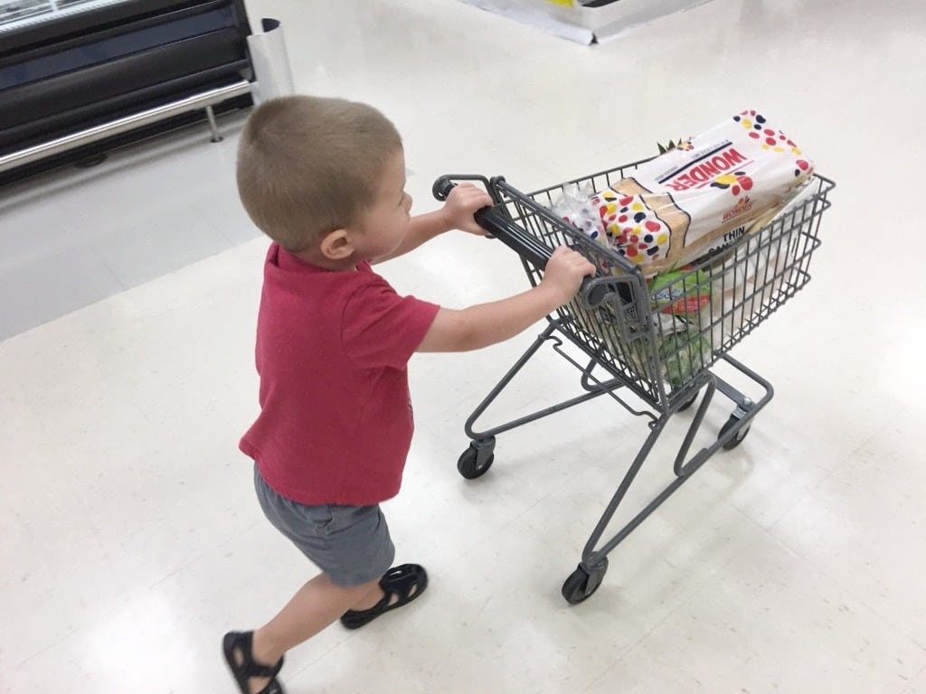 little boy pushing a toddler grocery cart