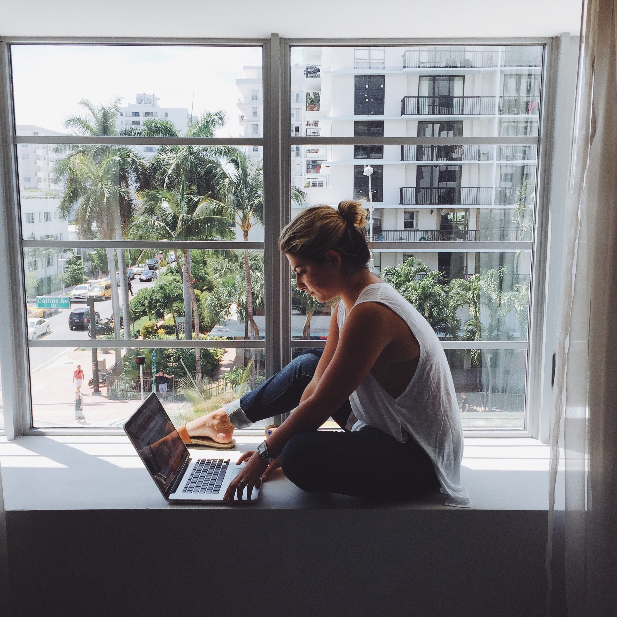 Woman sitting in front of window on laptop