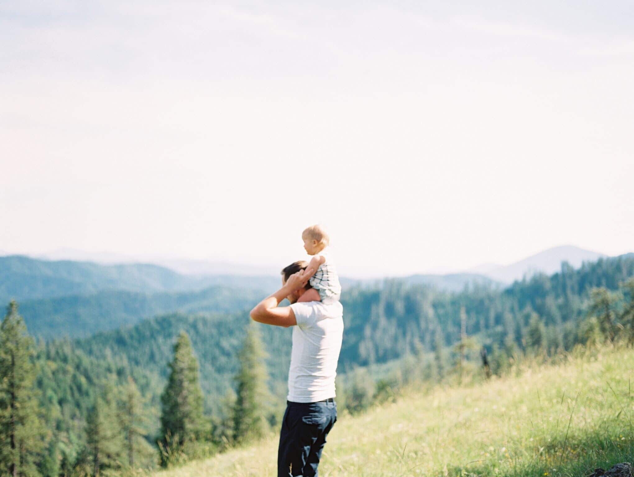 dad with child on his shoulders in a meadow