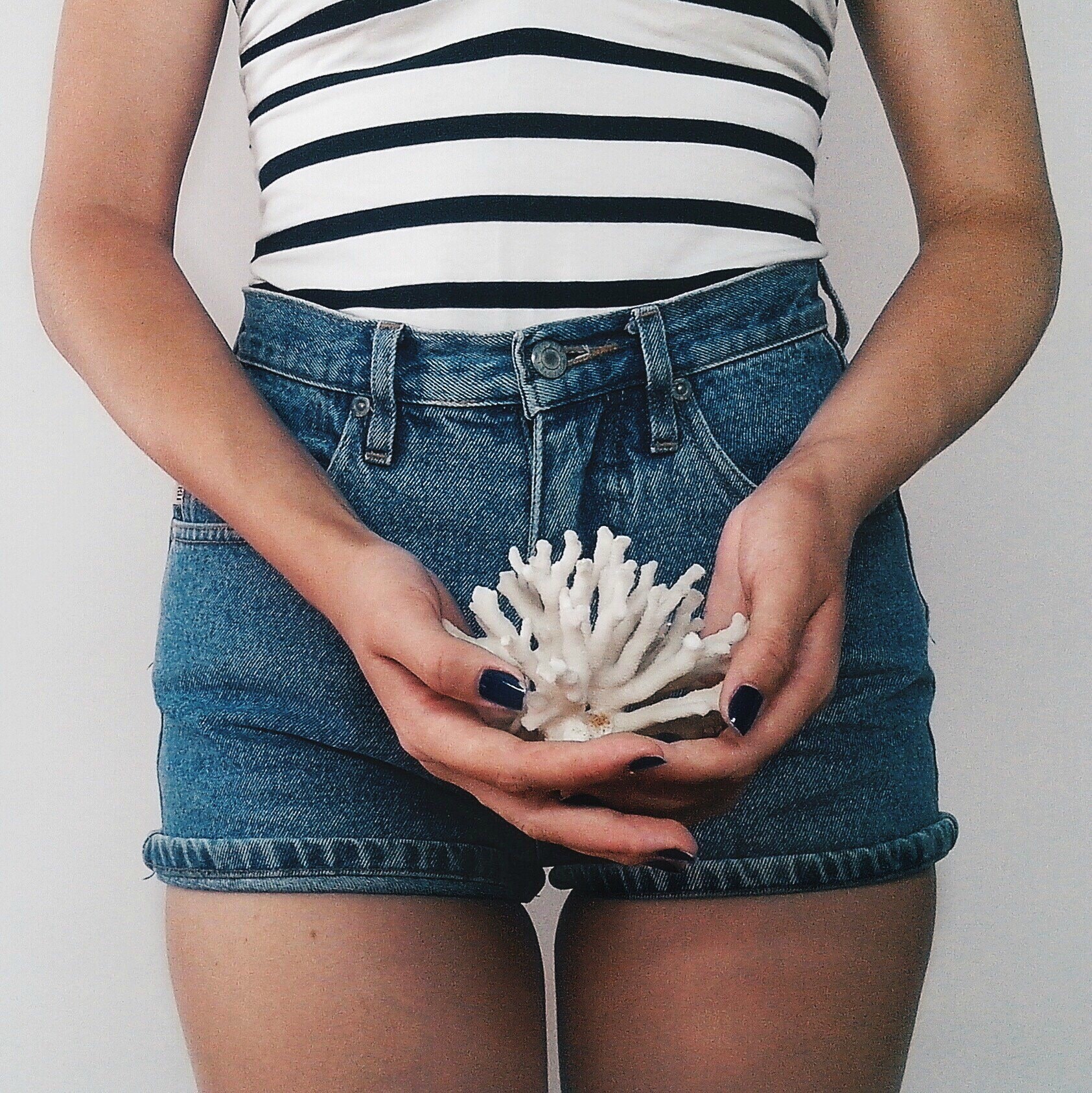 woman holding coral in front of her abdomen - the two week wait