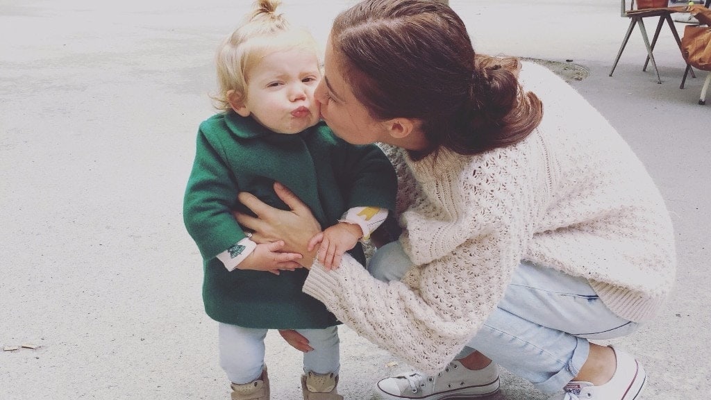 mom kissing little girl on the cheek