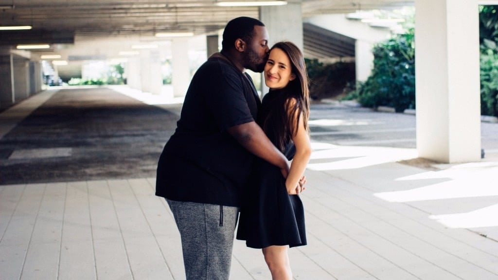 man kissing woman in a parking garage