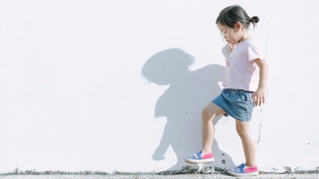 little girl playing on a sidewalk