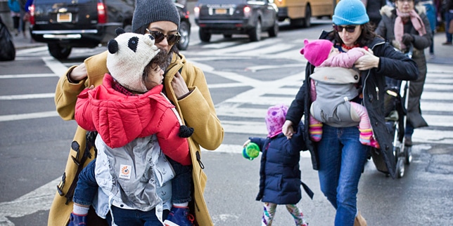 moms wearing hats and jackets walking with children on an nyc street, one of the best winter nyc activities for babies
